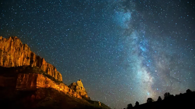 Milky Way over the red cliffs of a desert canyon at night
